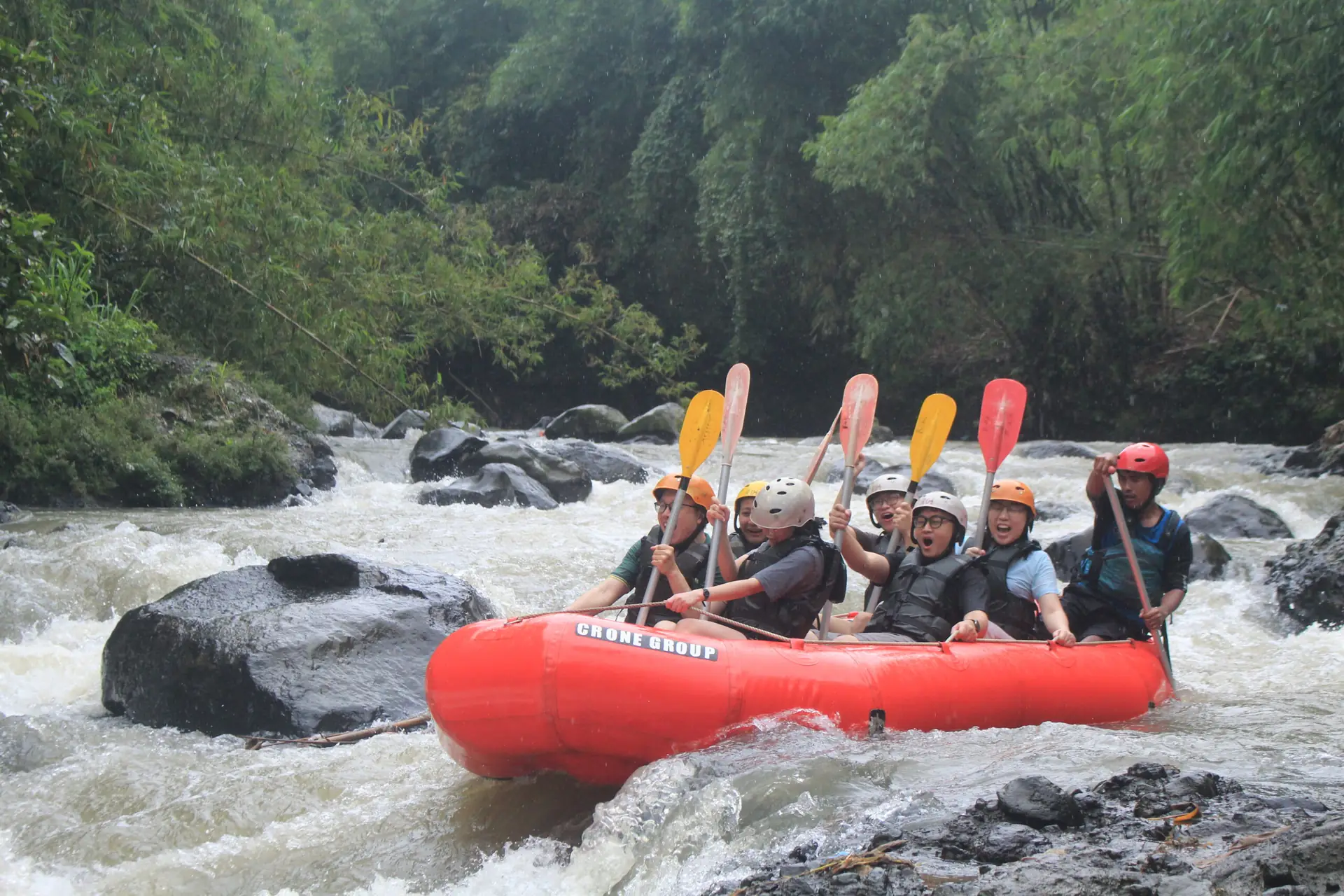 Perahu arung jeram merah berisi peserta melintasi sungai berbatu di Puncak Bogor